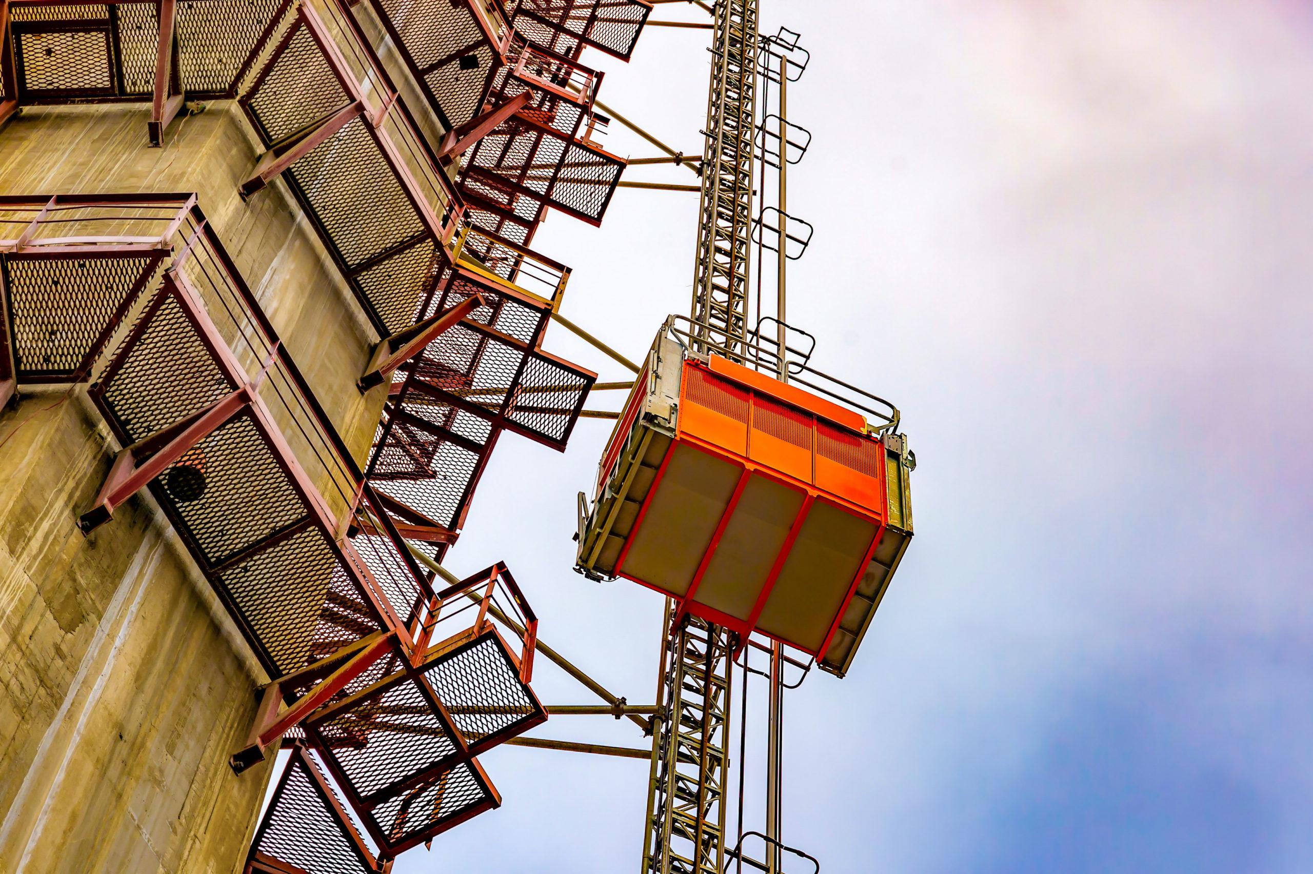 A construction elevator lifts workers to the height of a new cable-stayed bridge under construction. Construction equipment. The concept of high achievements.